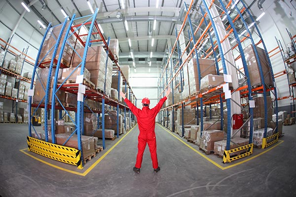 worker in red uniform raising hands in the middle of a warehouse