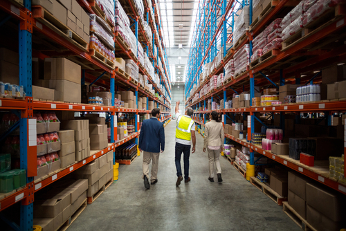 Rear view of warehouse team discussing while walking in warehouse