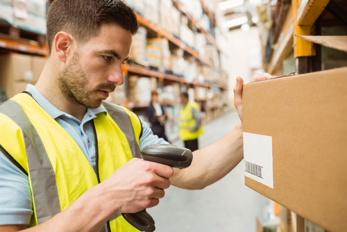 Warehouse worker scanning barcodes on boxes in a large warehouse
