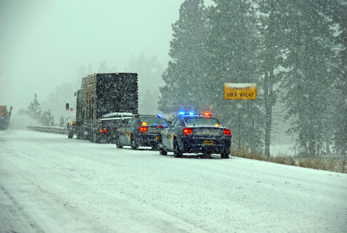 Police cars stop to assist a large truck during a winter storm