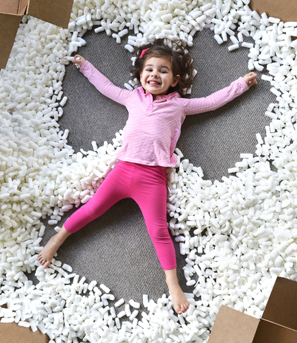 Child making snow angel with packing foam