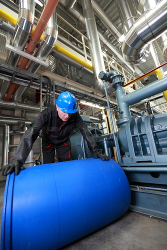 factory worker rolling plastic barrel