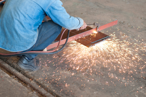 worker using oxyacetylene torch to cut plate