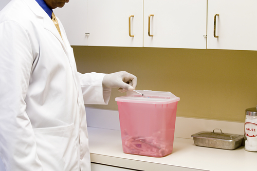 putting syringe in toxic waste bin