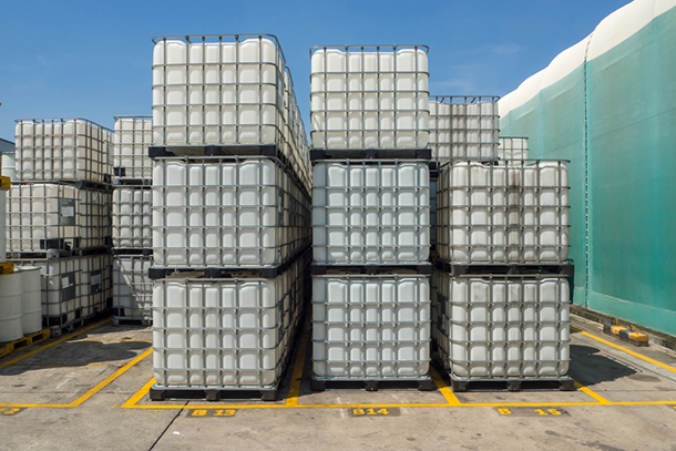 a group of stacked ibc totes outside of a warehouse