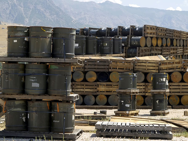a bunch of chemical barrels being stored on pallets outside